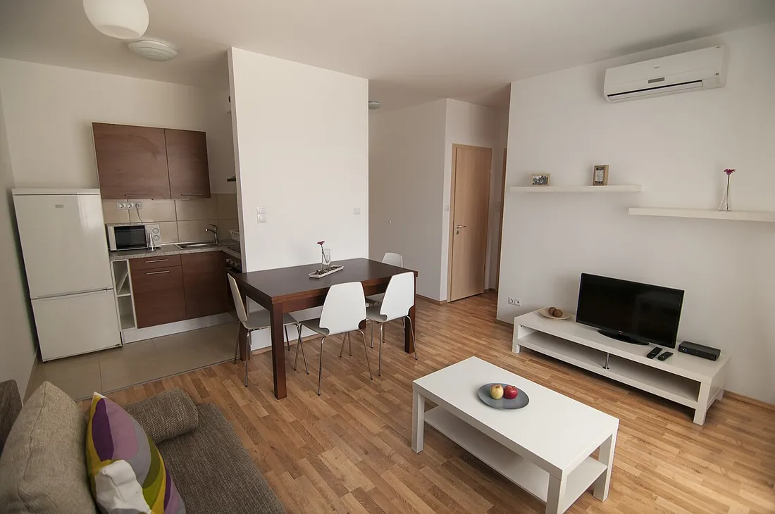 Salón comedor con cocina abierta, sofá, mesa y televisión