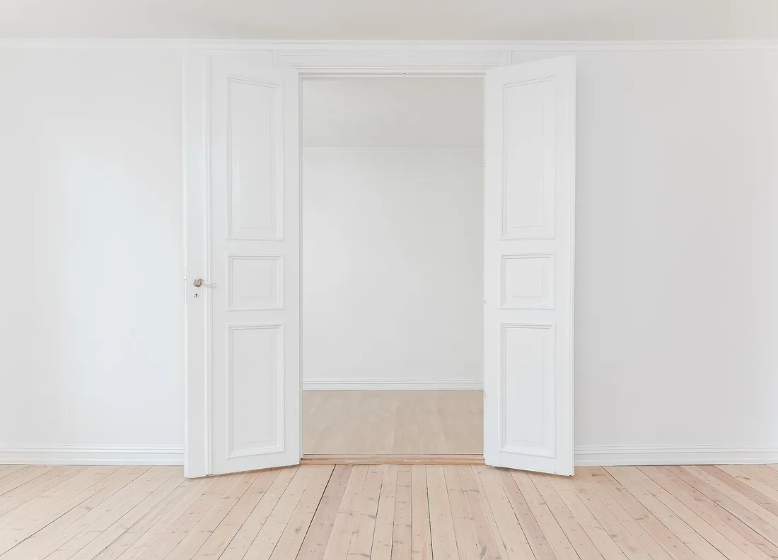 Habitación vacía con puertas abiertas y suelo de madera tras el vaciado