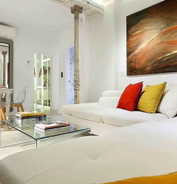 Salón con sofá blanco, mesa baja y cuadro, en una vivienda como las que vaciamos en el Eixample