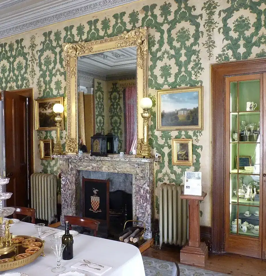 Comedor antiguo con chimenea, espejo y papel pintado, en una vivienda como las que vaciamos en Sants-Montjuïc