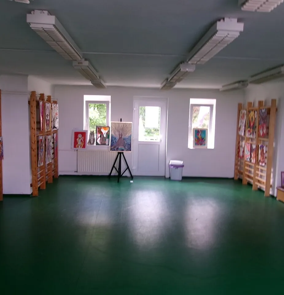 Sala diáfana con suelo verde y paneles expositores, en una vivienda como las que vaciamos en Sant Andreu
