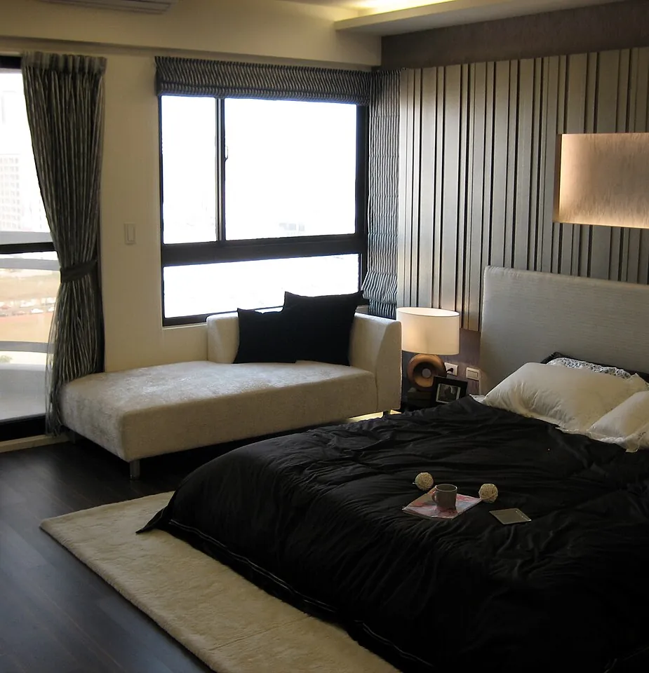 Dormitorio con cama baja, ventanal y lámpara, en una vivienda como las que vaciamos en L'Hospitalet de Llobregat