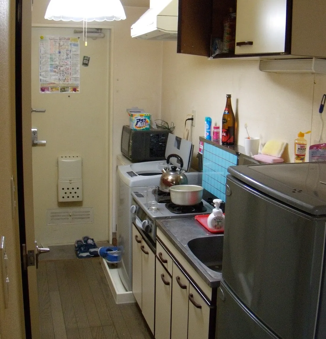 Cocina pequeña con nevera, microondas y enseres, en una vivienda como las que vaciamos en Sant Just Desvern